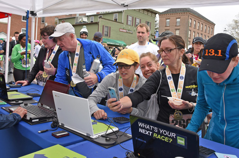 Runners, including Laura Ferrall (yellow hat) check out their times after the race.